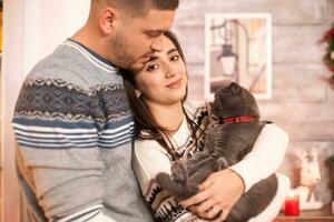 Happy man with his girlfriend and the cat on christmas day. photo