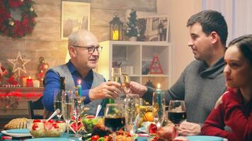 Zoom in shot of grandfather at family reunion for christmas celebration. Traditional festive christmas dinner in multigenerational family. Enjoying xmas meal feast in decorated room. Big family reunion photo