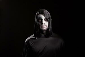 Portrait of man dressed up like angel of death over black background for halloween. photo