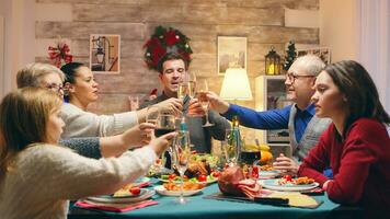 Little daughters sitting at the table with adults celebrating christmas. Traditional festive christmas dinner in multigenerational family. Enjoying xmas meal feast in decorated room. Big family reunion photo