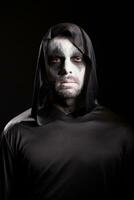 Grim reaper with a hood isolated over black background. Halloween costume. photo