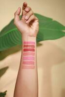 Lipstick swatches on woman hand on beige background. Lipstick color arm display contrast photo