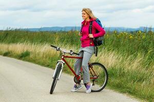 mujer caminante sentado en un bicicleta en el naturaleza foto