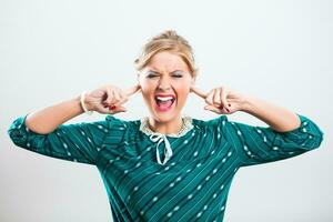 Retro woman shouting and covering her ears photo