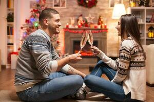 Cheerful couple laughing while clinking a glass of champagne celebrating christmas. photo