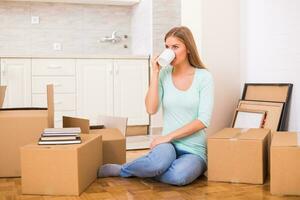 Beautiful woman drinking coffee while moving into her new apartment. photo