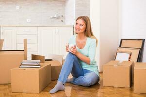 Beautiful woman drinking coffee while moving into her new apartment. photo