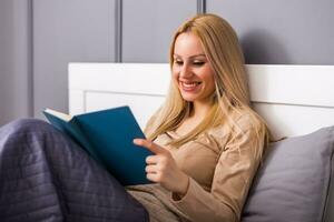 Beautiful woman enjoys reading a book at her bedroom . photo