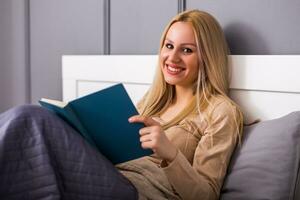 Beautiful woman enjoys reading a book at her bedroom . photo