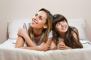 Happy mother and daughter lying in bed photo