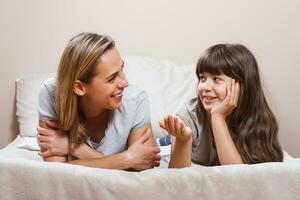 Happy mother and daughter talking in bed photo