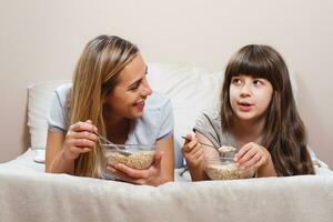 madre y hija teniendo sano desayuno en cama foto