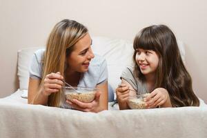 madre y hija teniendo sano desayuno en cama foto