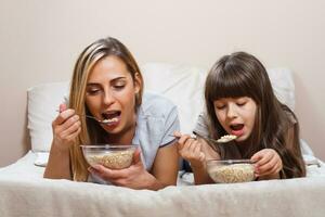 madre y hija teniendo sano desayuno en cama foto