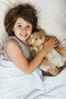 Little girl in bed with her teddy bear photo