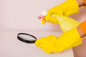 Image of housewife cleaning table with spray bottle and magnifying glass. photo