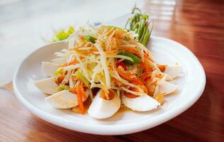 Papaya salad with salted egg is a combination of Thai papaya salad with dried shrimp and garnished with salted egg. Garnish with roasted peanuts. photo