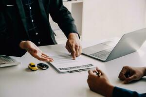 A car rental company employee is handing out the car keys to the renter after discussing the rental details and conditions together with the renter signing a car rental agreement. Concept car rental. photo