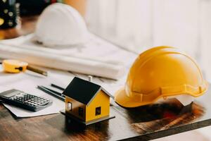 arquitecto hombre trabajando con ordenador portátil y planos, ingeniero inspección en lugar de trabajo para arquitectónico plan, bosquejo un construcción proyecto ,selectivo foco,negocio concepto Clásico color foto