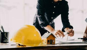 arquitecto hombre trabajando con ordenador portátil y planos, ingeniero inspección en lugar de trabajo para arquitectónico plan, bosquejo un construcción proyecto ,selectivo foco,negocio concepto Clásico color foto