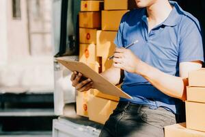 SME entrepreneur Small business entrepreneurs Online selling ideas,Happy Young Asian business owner work on computer and a boxs at home,delivery SME procurement package box deliver to customers, photo