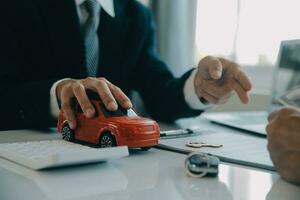 Closeup asian male people car salesman or sales manager offers to sell a car and explains and reads the terms of signing a car contract and insurance. photo