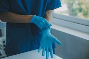 médico o enfermero poniendo en azul nitrilo quirúrgico guantes, profesional médico la seguridad y higiene para cirugía y médico examen en blanco antecedentes. foto