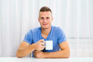Young man enjoys drinking coffee at home. photo