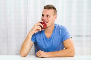 joven hombre comiendo manzana a hogar. foto