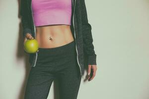 Fit sporty woman with abs holding apple.Toned photo. photo