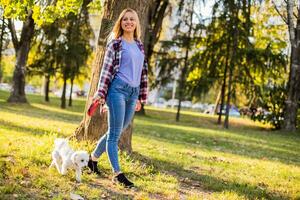 Beautiful woman walking with her Maltese dog in the park. photo