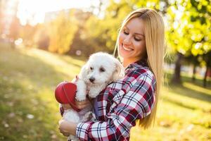 Beautiful woman spending time with her Maltese dog outdoor. photo