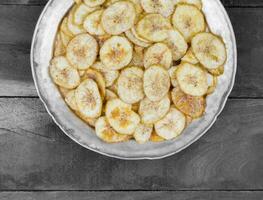 Banana Chips Popular Deep Fried Tea Time Snack on Dark Wooden Background photo