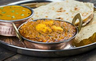 Indian Traditional Thali Food Kadai Paneer Served With Dal Makhani on Vintage Wooden Background photo