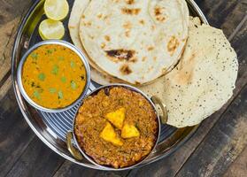 Indian Traditional Thali Food Kadai Paneer Served With Dal Makhani on Vintage Wooden Background photo