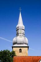 un Iglesia campanario con un reloj en parte superior foto