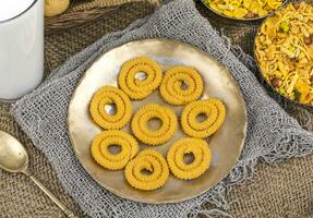 Indian Traditional Deep Fried Snack Chakli with Namkeen on Vintage Background photo