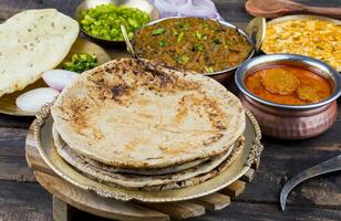 indio cocina chapati con sev tamatar, gatta curry, raita, papad o cebolla en de madera antecedentes foto