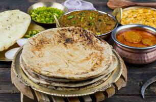 indio cocina chapati con sev tamatar, gatta curry, raita, papad o cebolla en de madera antecedentes foto