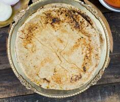 indio cocina chapati con sev tamatar, gatta curry, raita, papad o cebolla en de madera antecedentes foto