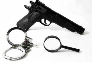 a handgun, handcuffs and a magnifying glass photo