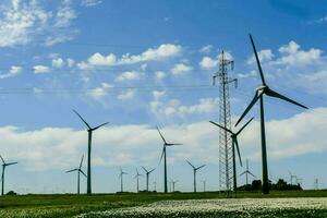 viento turbinas en un campo con azul cielo y blanco flores foto