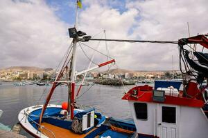 a fishing boat docked in the harbor with a city in the background photo