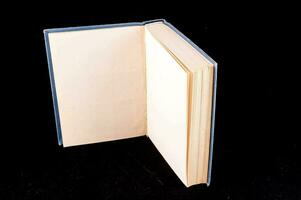 un abierto libro con blanco paginas en un negro antecedentes foto