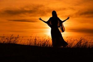 silueta de un mujer disfruta meditar a hermosa puesta de sol. foto