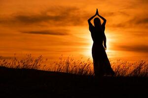 Silhouette of a woman enjoys meditate  at beautiful sunset. photo