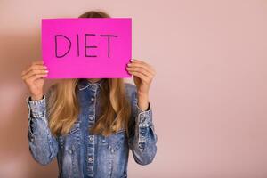 Woman covering her face with paper with word diet. photo