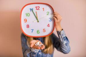 Woman holding broken cigarettes and clock in front of the wall.Quitting smoking concept. photo