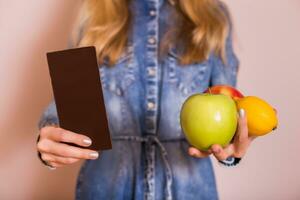 Woman holding chocolate and fruit.It is time for diet and healthy eating concept. photo