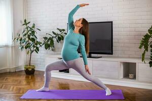 hermosa embarazada mujer disfruta hacer ejercicio yoga a su hogar. foto